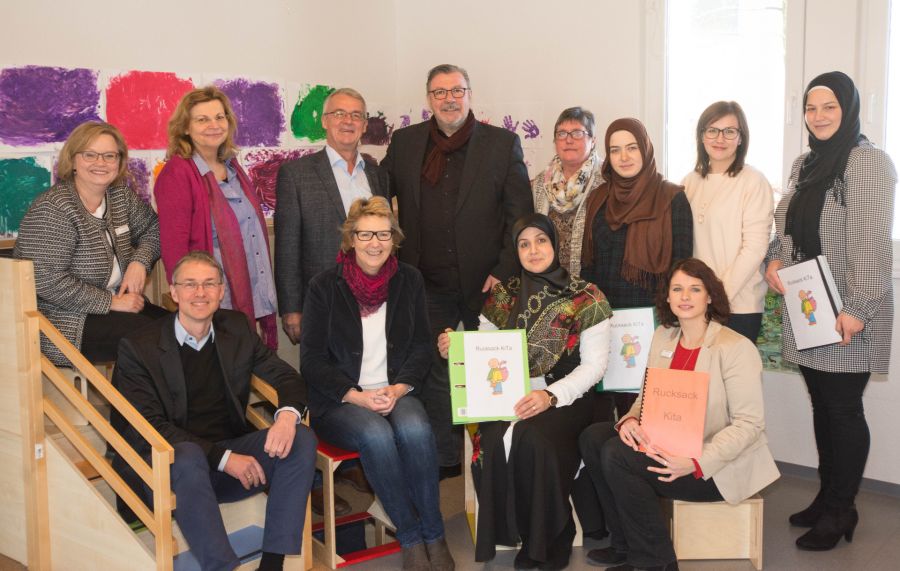 Hintere Reihe, von links: Rita Schinschke (Leiterin der Kita Mistelweg), Hildegard König (Jugendamt Stadt Paderborn), Dr. Burghard Lehmann (Geschäftsführer Osthushenrich-Stiftung), Bernhard Lünz (Geschäftsführer des Kommunalen Integrationszentrums), Susanne Niggemeier (Jugendamt Stadt Paderborn), Amina Asheer (Mutter), Olga Kroll (Projektkoordinatorin Rucksack Kita), Manal Mustafa (Mutter), vordere Reihe, von links: Dr. Oliver Vorndran (Leiter des Bildungs- und Integrationszentrums Kreis Paderborn), Angelika Berns (Jugendamt Stadt Paderborn), Rana Kabalan (Elternbegleiterin), Antje Müller (Erzieherin, stellvertretende Leiterin der Kita Mistelweg). (Foto: Amt für Presse- und Öffentlichkeitsarbeit, Kreis Paderborn, Anna-Sophie Schindler) Hintere Reihe, von links: Rita Schinschke (Leiterin der Kita Mistelweg), Hildegard König (Jugendamt Stadt Paderborn), Dr. Burghard Lehmann (Geschäftsführer Osthushenrich-Stiftung), Bernhard Lünz (Geschäftsführer des Kommunalen Integrationszentrums), Susanne Niggemeier (Jugendamt Stadt Paderborn), Amina Asheer (Mutter), Olga Kroll (Projektkoordinatorin Rucksack Kita), Manal Mustafa (Mutter), vordere Reihe, von links: Dr. Oliver Vorndran (Leiter des Bildungs- und Integrationszentrums Kreis Paderborn), Angelika Berns (Jugendamt Stadt Paderborn), Rana Kabalan (Elternbegleiterin), Antje Müller (Erzieherin, stellvertretende Leiterin der Kita Mistelweg). (Foto: Amt für Presse- und Öffentlichkeitsarbeit, Kreis Paderborn, Anna-Sophie Schindler)